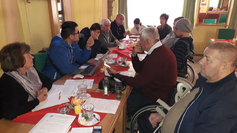 Slika. Koalicija organizacija osoba sa invaliditetom regije Doboj 10. oktobra 2019. godine organizovala sastanak svojih članica.Na sastanku su predstavljeni rezultati ostvareni kroz aktivnosti koje su realizovane u ovoj godini. Slika učesnika/ca sastanka u restoranu koji sjede za dugim stolom.