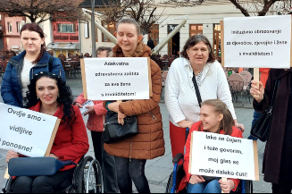 Slika nastala tokom Osmomartovskog marša na Trgu Slobode u Tuzli, na kojem članice foruma drže transparente sa svojim porukama za poštivanje prava žena s invaliditetom.