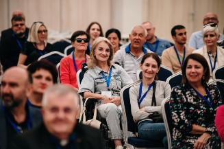 Slika nastala tokom drugog kongresa OSI u BiH, u konferncijskoj sali Hotela Neum. Na slici je 17 osoba, 10 žena i 7 muškaraca koje sjede na stolicam, svi su nasmijani i gledaju u pravcu osobe koja ih fotografiše. 